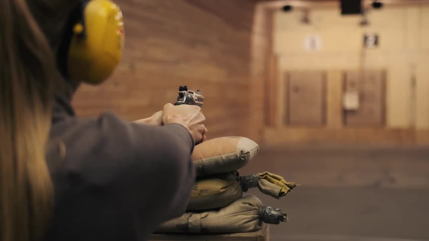 A woman is firing a gun in the gun range