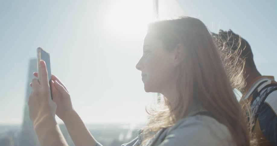 Woman takes a picture of the city below with her phone