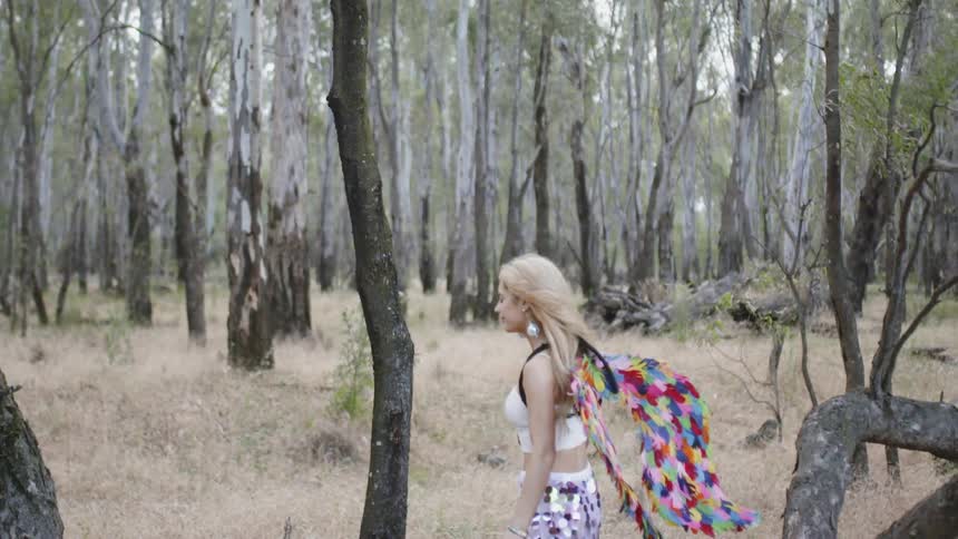 A woman with paper wings walks in the forest