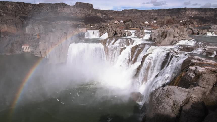A rainbow forms near waterfalls