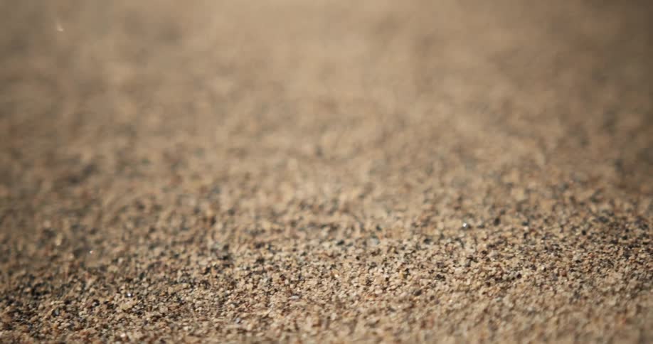 The wind is blowing the sand on the ground