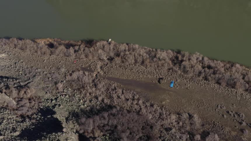 A person paraglides down by the water