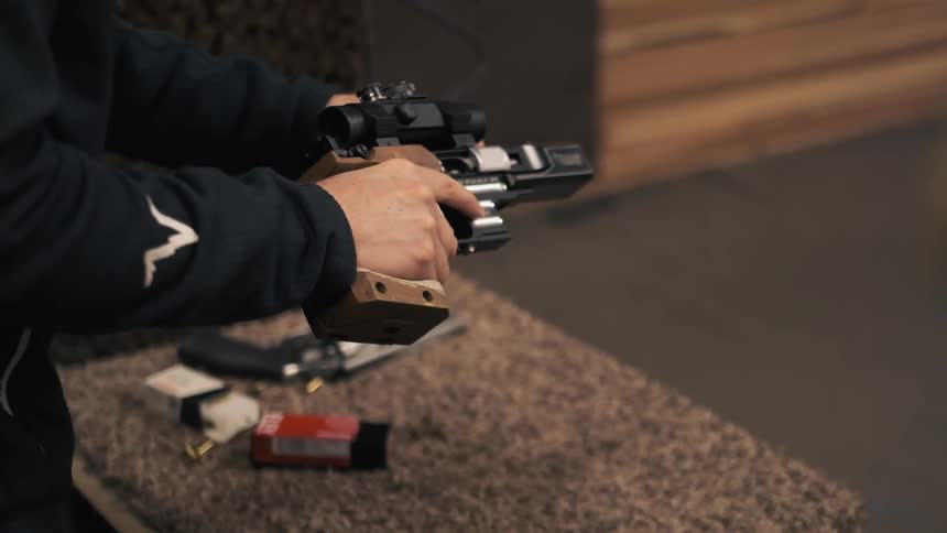 A person lifts the gun from the counter in the firing range