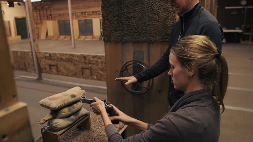 A woman is aiming a gun in the firing range