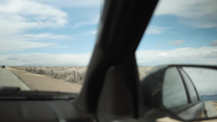 The vehicles travel down the road by the desert