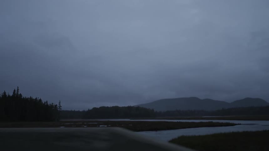 A landscape of hills, trees and lake water on an overcast day