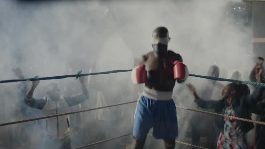 A crowd cheers at an outdoor boxing match