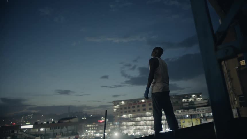Man stands on a building rooftop at dusk