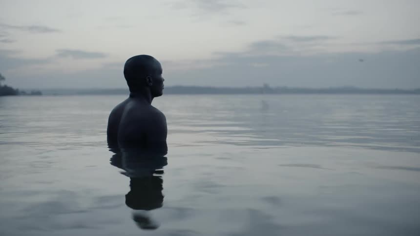 Man standing in the water at sunset