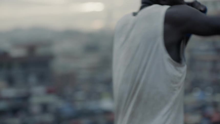 Man practices punching while standing on a rooftop overlooking a city