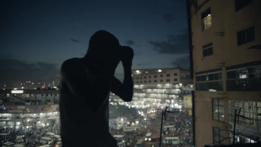 Man practices punching while standing on a rooftop overlooking a city