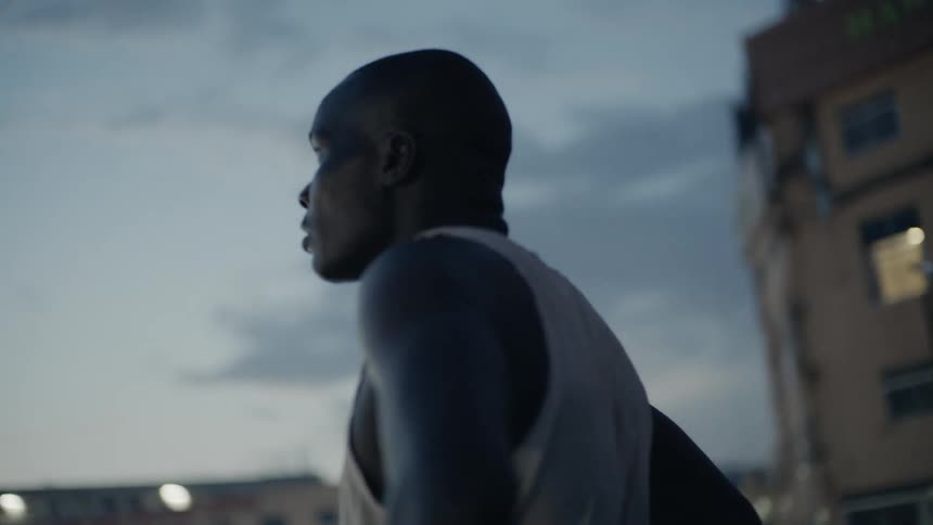 Man stands on a rooftop looking out at sunset