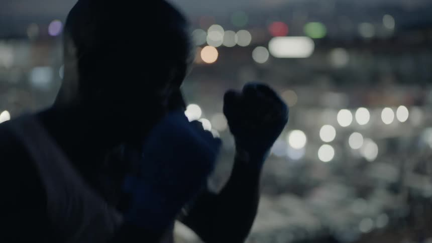 Man punches at night with lights in the city shining below
