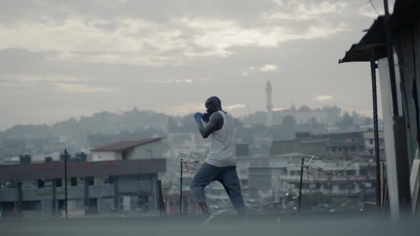 A boxer punches the air on a building rooftop