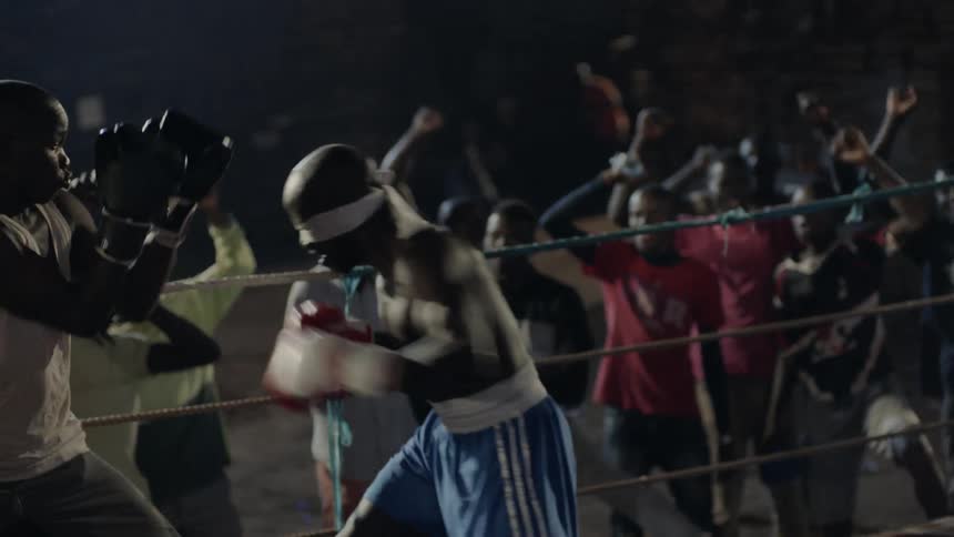 A crowd cheers at an outdoor boxing match