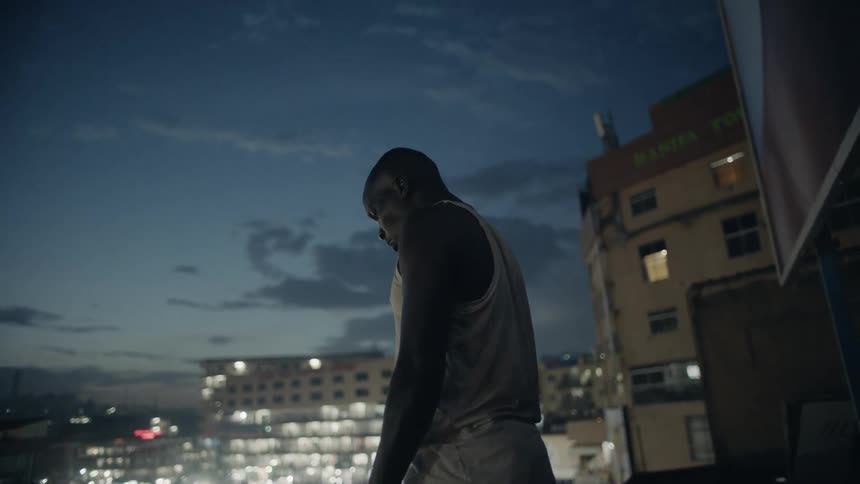 Man standing on rooftop at night looking over city