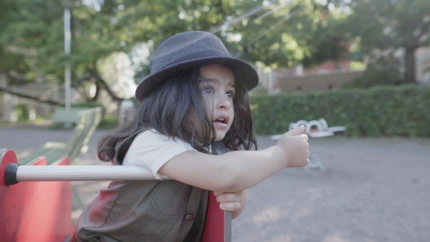 A young child pointing pointing into the distance while playing on playground rocker.