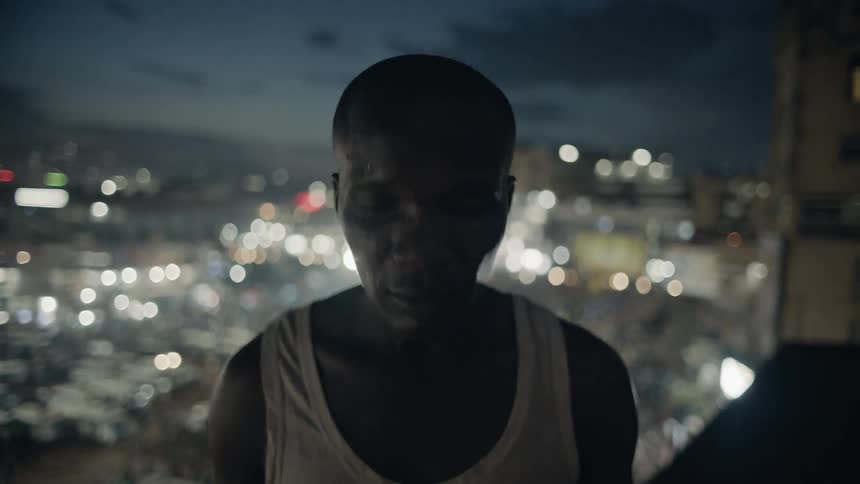 A man stands on a building rooftop at night
