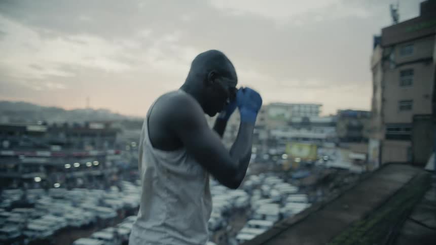 A boxer punches the air on a building rooftop