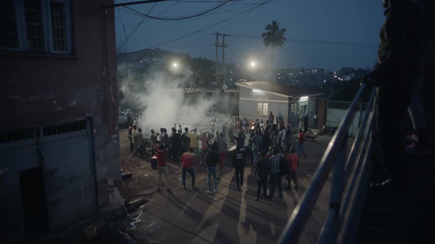Crowd cheers standing around a boxing ring at night