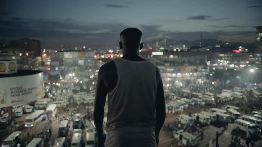 A man stands on a building rooftop at night