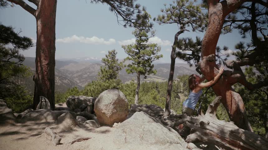 Woman ties a hammock to a tree in mountains