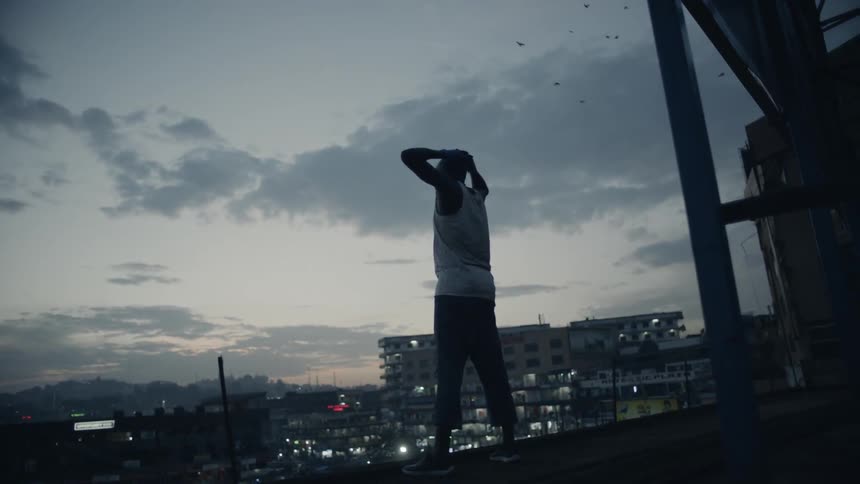 Man stands on a building rooftop at dusk