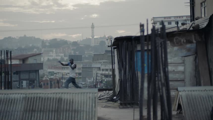 A boxer punches the air in a city at sunset