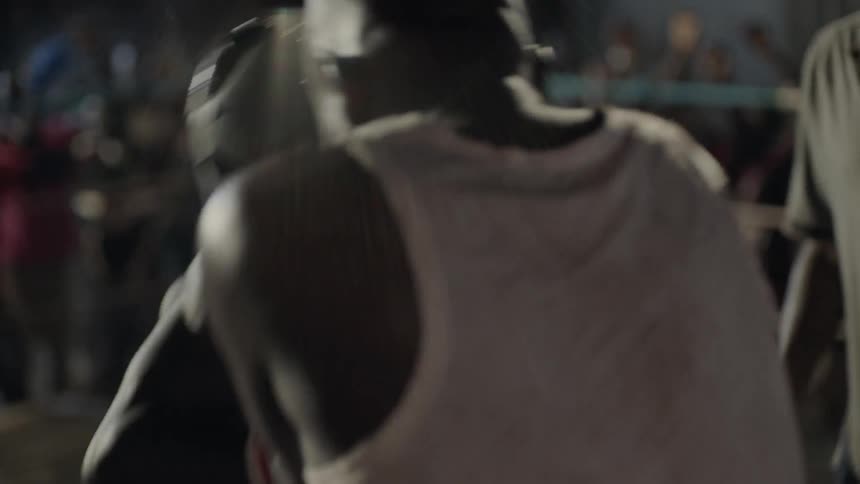 Two boxers are fighting in a ring outside at night