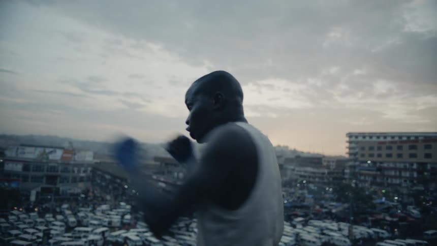Man practices punching while standing on a rooftop overlooking a city