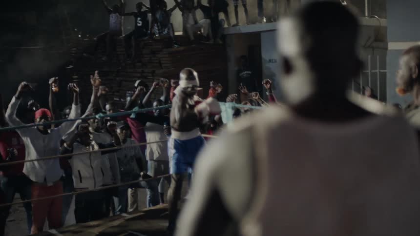 Two men prepare for boxing match while crowd cheers on