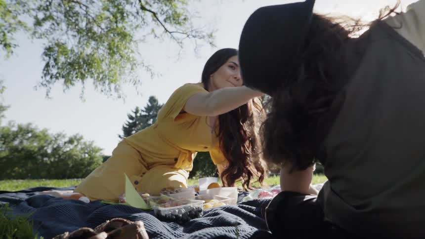 A young mother reaching out to touch her child's hair at picnic.