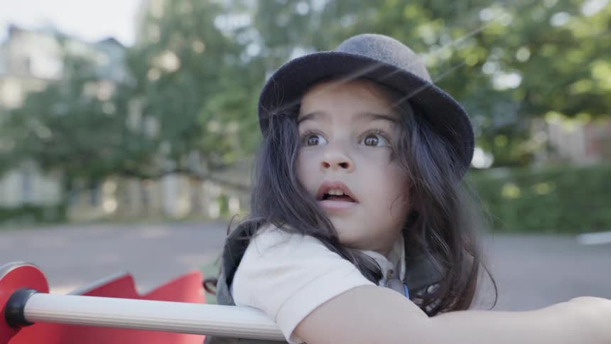 A young child looking up with a curious expression on playground equipment.