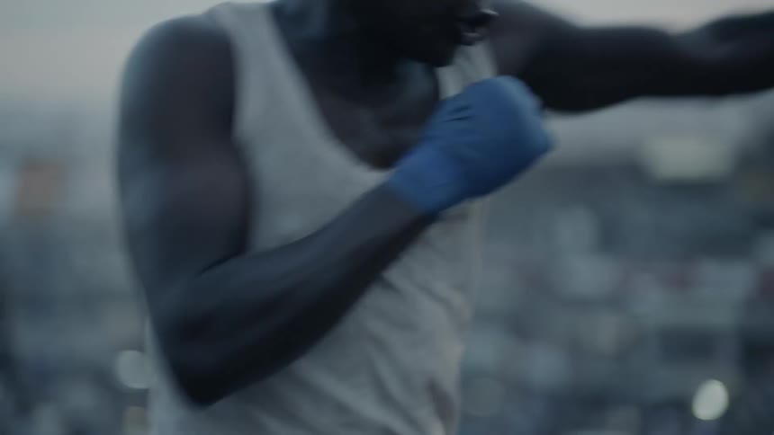 Man punches while standing on a rooftop at sunset