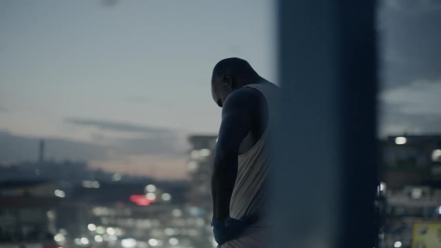 A man stands on a building rooftop at dusk