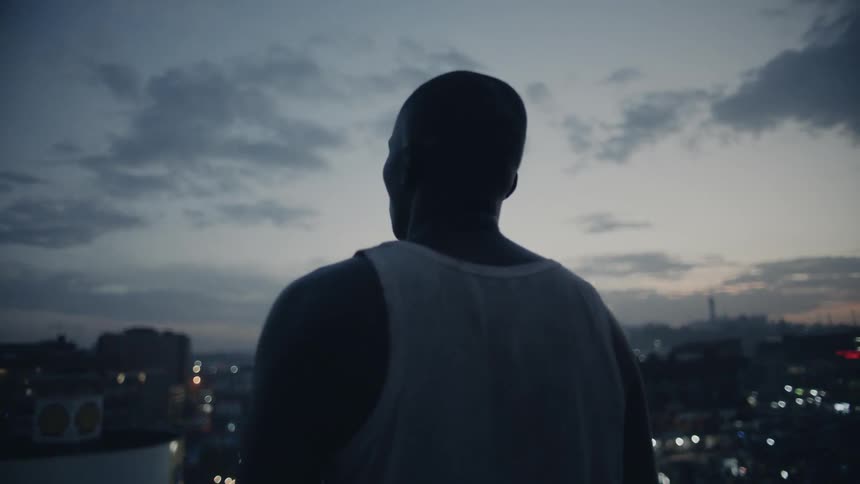 Man stands on a building rooftop at dusk