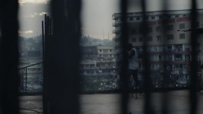 Man practices punching while standing on a rooftop overlooking a city