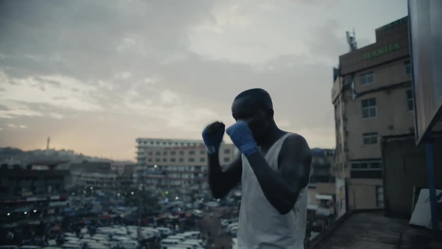 Man practices punching while standing on a rooftop overlooking a city