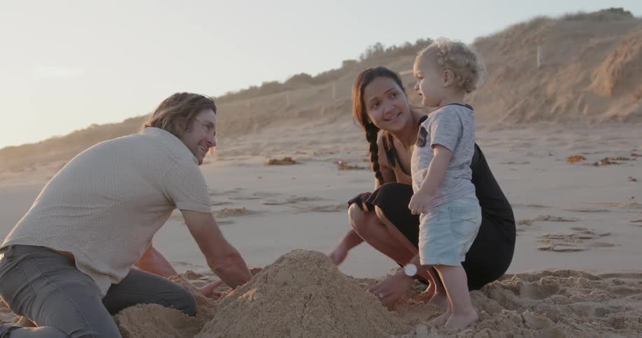 A young family builds a sandcastle on a beach