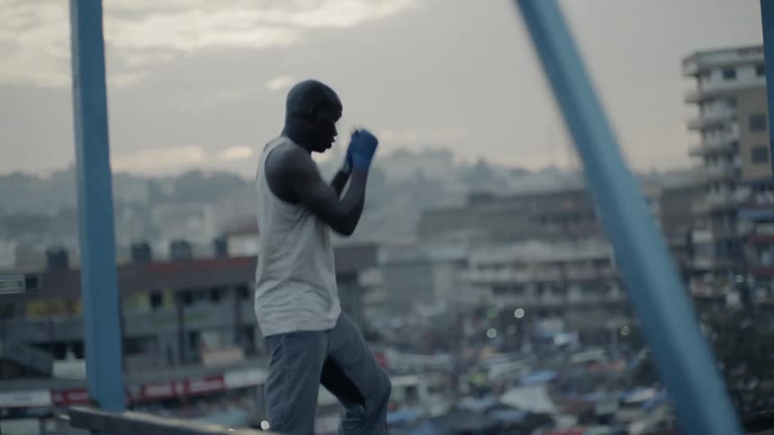 A boxer punches the air on a building rooftop