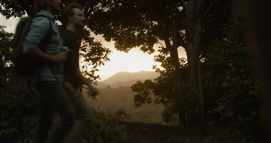 Two men hike in mountains at sunset