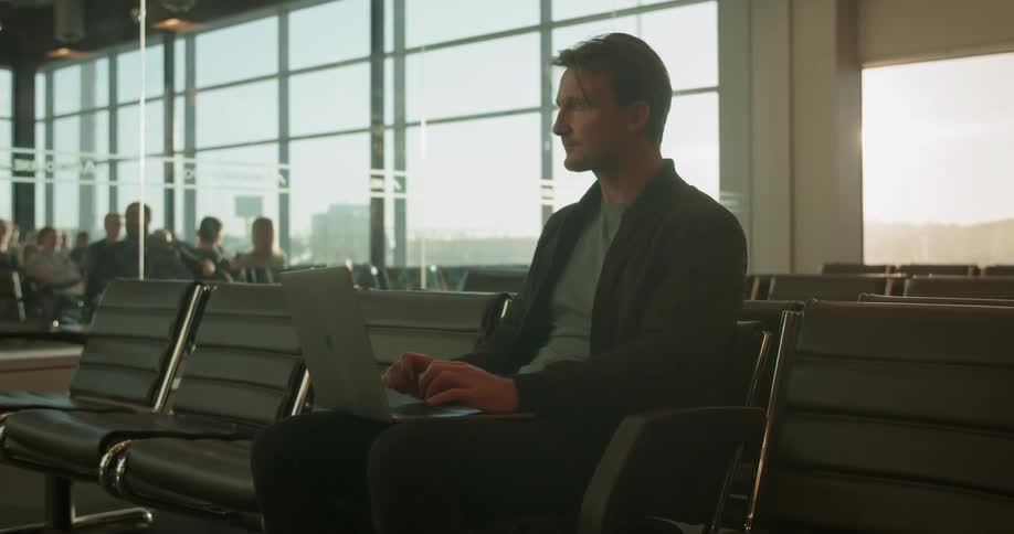 A man types on a laptop in an airport