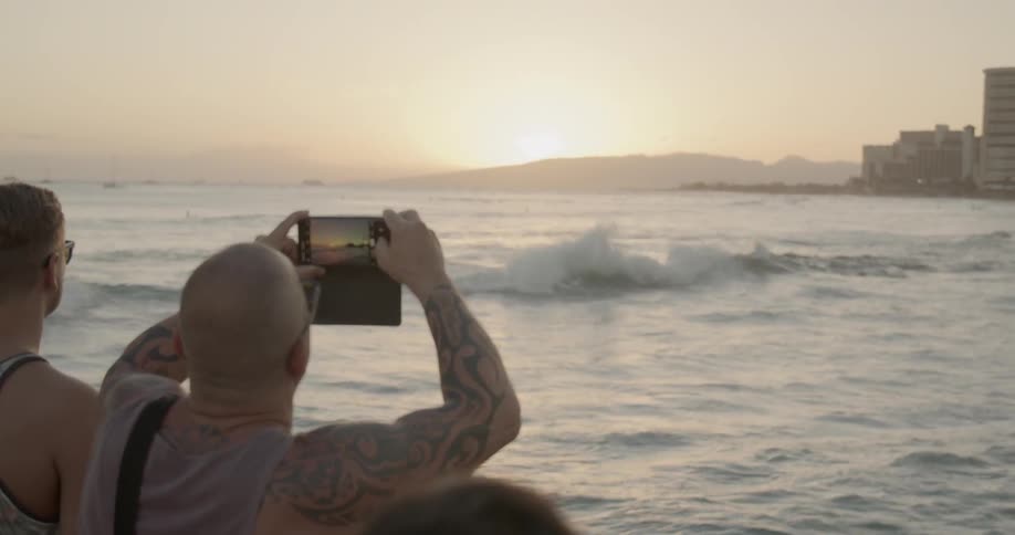 People photograph a beach at sunset