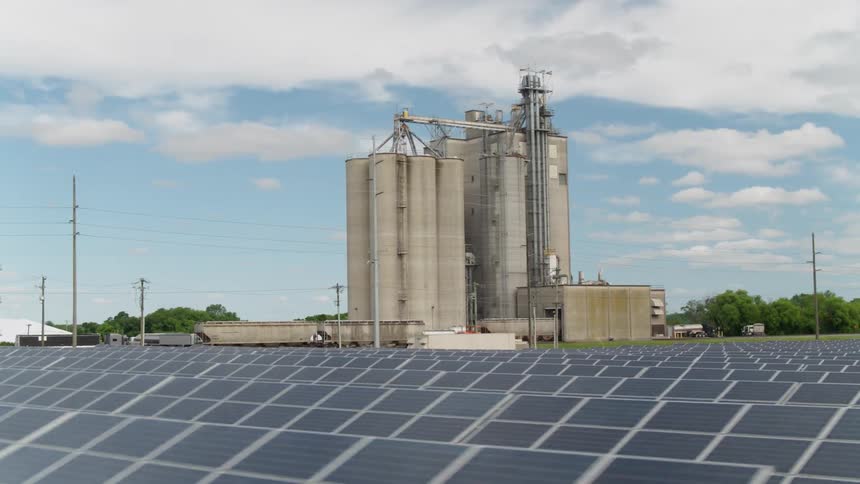 Panels cover crops and large silos stand nearby