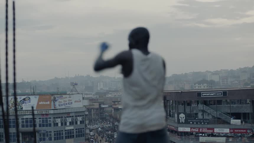 Man practices punching while standing on a rooftop overlooking a city