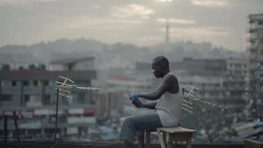 A man is wrapping his hands with tape while sitting outside near dusk