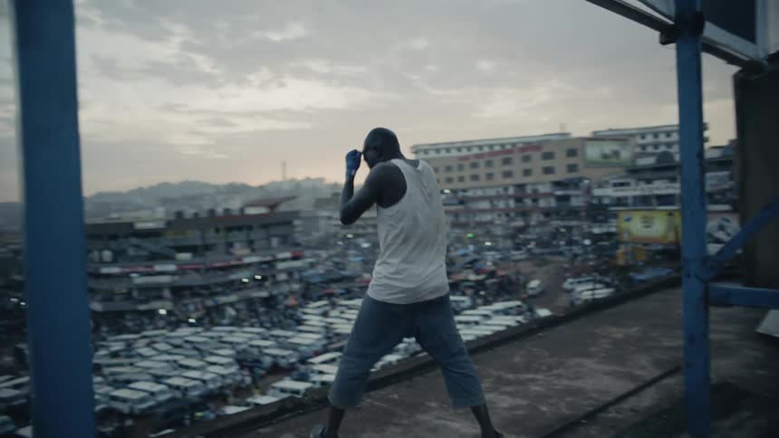 A boxer is shadow boxing on a rooftop at sunset
