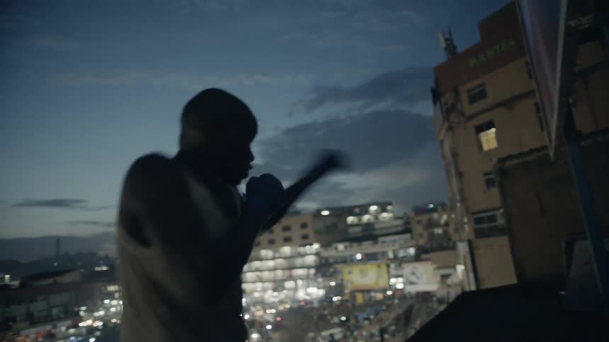 A boxer punches the air on a building rooftop