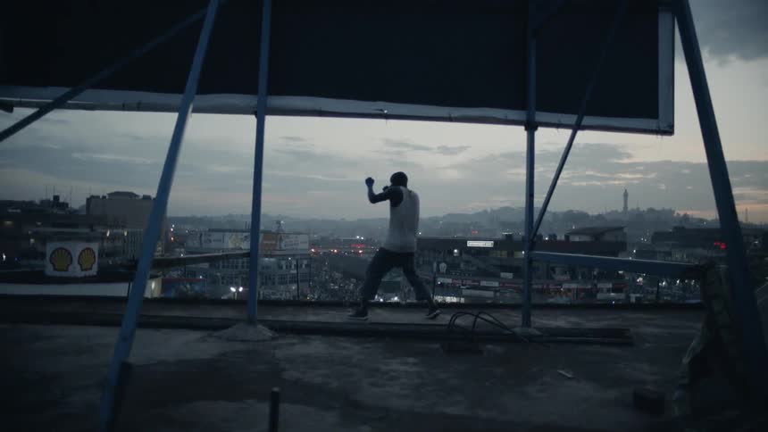 Man practices punching while standing on a rooftop overlooking a city