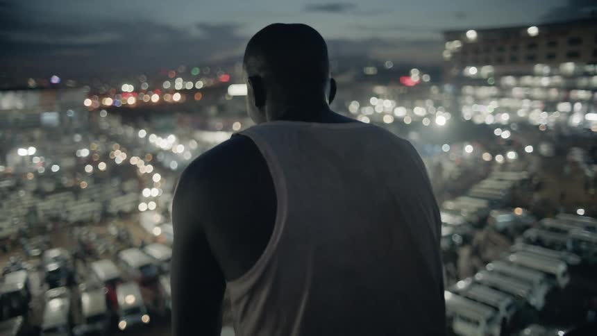 Man stands on a building rooftop at dusk